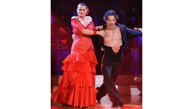 Ein Mann und eine Frau tanzen in auffälligen Kostümen auf einer Bühne.