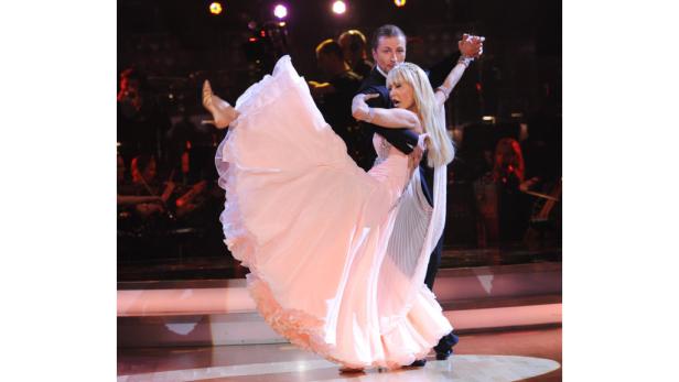 Ein Tanzpaar führt eine Hebefigur auf einer Bühne auf..