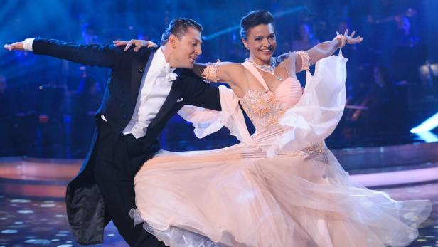 Ein Tanzpaar führt einen eleganten Walzer auf einer Bühne auf.