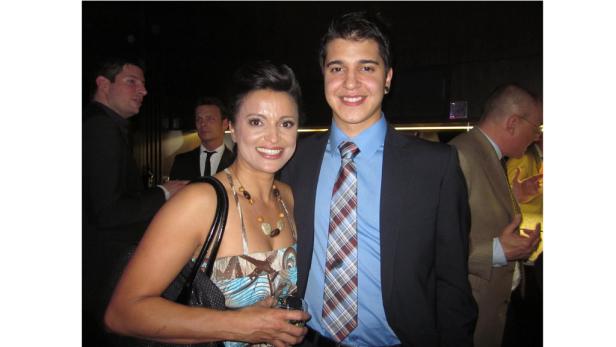 Eine Frau und ein junger Mann posieren lächelnd für ein Foto auf einer Veranstaltung.