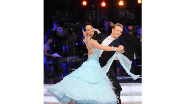 Ein Paar tanzt auf einer Bühne, die Frau in einem hellblauen Kleid.