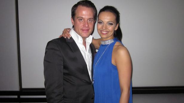 Ein Mann im Anzug posiert mit einer Frau in einem blauen Kleid.