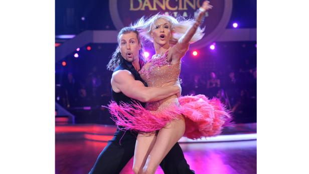 Ein Tanzpaar führt eine energiegeladene Performance auf einer Bühne auf.