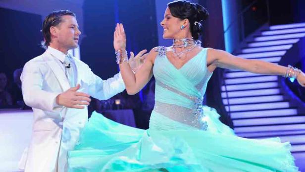 Ein Tanzpaar in festlicher Kleidung auf einer Bühne.
