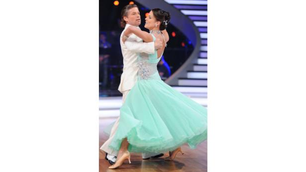 Ein Mann im weißen Anzug tanzt mit einer Frau in einem mintgrünen Ballkleid.