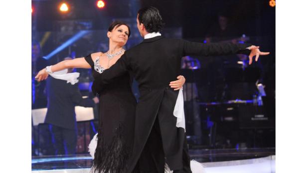 Ein Tanzpaar führt auf einer Bühne einen eleganten Tanz auf.