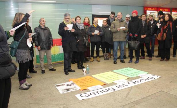 Eine Gruppe von Menschen demonstriert mit kurdischen Flaggen und Schildern, auf denen „Genug ist Genug!“ steht.