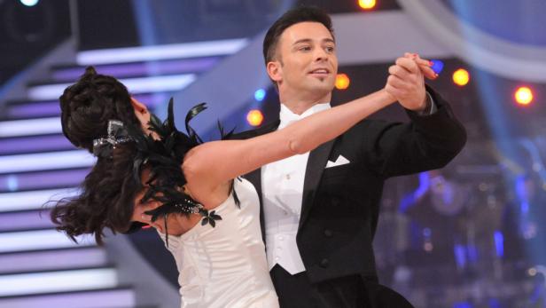 Ein Mann im Smoking tanzt mit einer Frau in einem weißen Kleid.