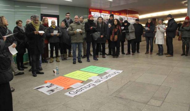 Eine Gruppe von Menschen steht um Schilder mit der Aufschrift „Genug ist Genug!".