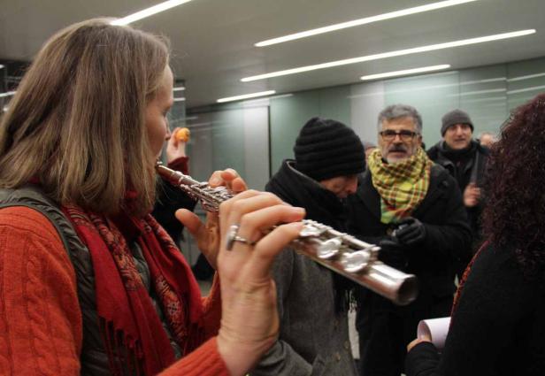 Eine Frau spielt Querflöte in einer Menschenmenge.