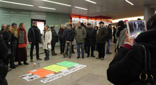 Eine Gruppe von Menschen demonstriert mit Schildern, auf denen „Genug ist Genug!“ steht.