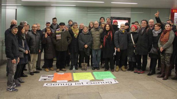 Eine Gruppe von Menschen steht mit Schildern mit der Aufschrift „Genug ist Genug!“.
