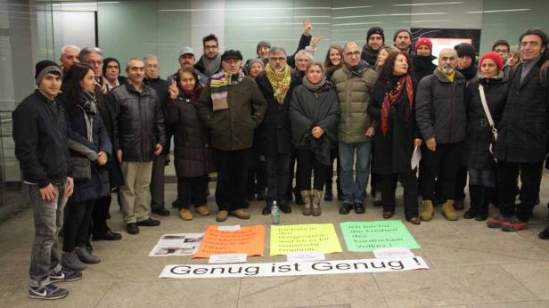 Eine Gruppe von Menschen demonstriert mit Schildern, auf denen „Genug ist Genug!“ steht.