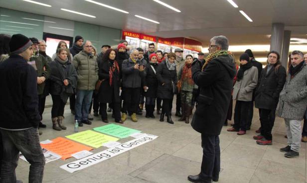 Eine Gruppe von Menschen steht um Schilder mit der Aufschrift „Genug ist Genug!“.