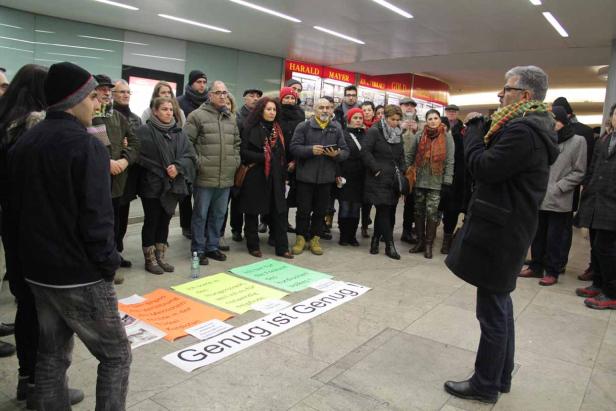 Eine Gruppe von Menschen demonstriert mit Schildern, auf denen „Genug ist Genug“ steht.