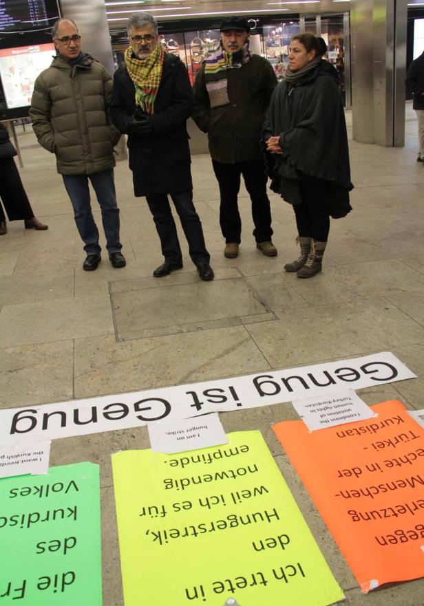 Eine Gruppe von Menschen steht vor Protestschildern mit der Aufschrift „Genug ist Genug“.