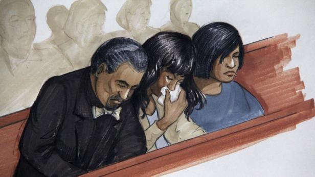 Eine Frau weint mit einem Taschentuch in der Hand, während zwei Männer neben ihr sitzen.