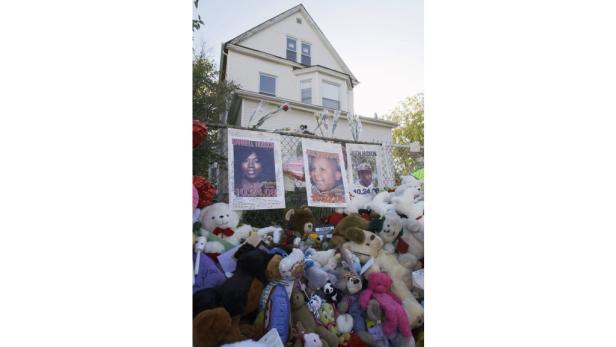 Eine Gedenkstätte mit Fotos von Darnell Hudson, Julian King und Jason Hudson vor einem Haus.