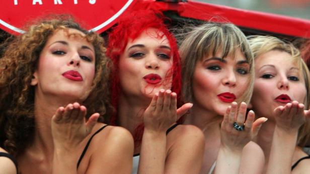 Vier Frauen mit rotem Lippenstift schicken Luftküsse.