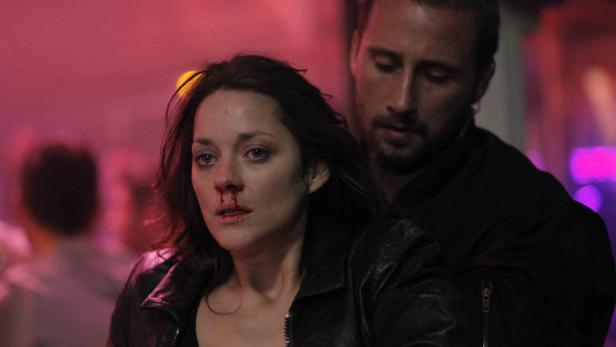 Marion Cotillard mit blutiger Nase, von einem Mann im Hintergrund gehalten.