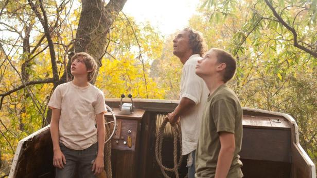 Matthew McConaughey steht mit zwei Jungen in einem alten Boot und schaut nach oben.