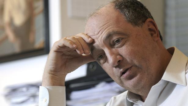 Ein Mann in einem hellen Hemd stützt seinen Kopf mit der Hand.