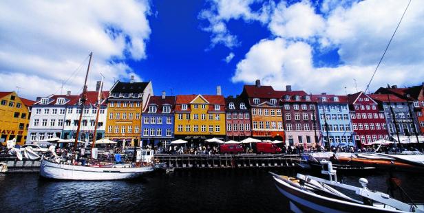 Bunte Häuserfassaden und Boote im Nyhavn, Kopenhagen, unter blauem Himmel.