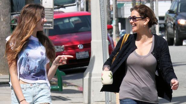 Eine junge Frau zeigt auf eine andere Frau, die eine Tasse in der Hand hält und lächelt.