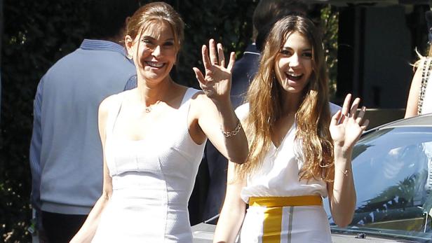 Zwei lächelnde Frauen winken in die Kamera.