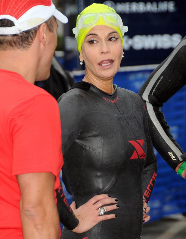 Eine Frau in einem Triathlon-Anzug und gelber Badekappe unterhält sich mit einem Mann.