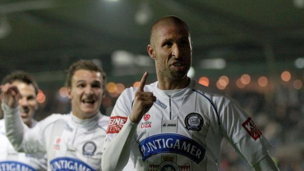 Ein Fußballspieler in weißem Trikot mit dem Schriftzug „Puntigamer“ feiert mit seinen Teamkollegen.