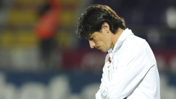 Ein Mann in weißer Jacke mit gesenktem Kopf.