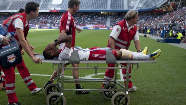 Sanitäter schieben einen verletzten Fußballspieler auf einer Trage vom Spielfeld.