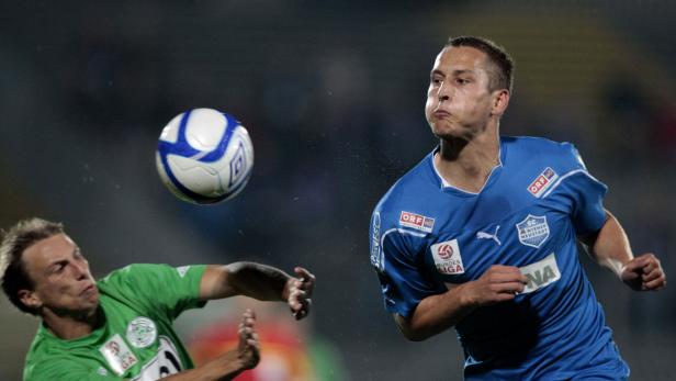 Zwei Fußballspieler kämpfen um den Ball während eines Spiels.