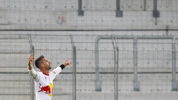 Ein Fußballspieler jubelt mit erhobenen Armen auf dem Spielfeld.