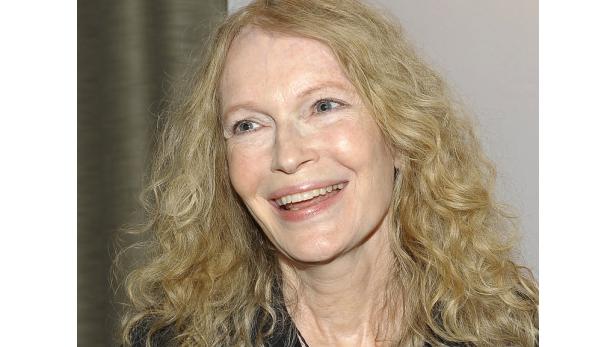 Nahaufnahme von Mia Farrow mit blond gelocktem Haar und einem freundlichen Lächeln.