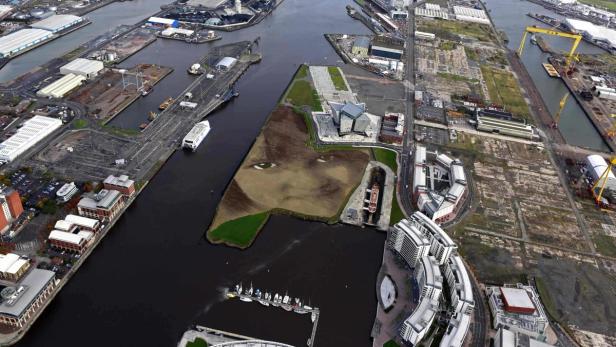 Luftaufnahme von Belfast mit einem riesigen Porträt von einem Gesicht auf einem Feld.