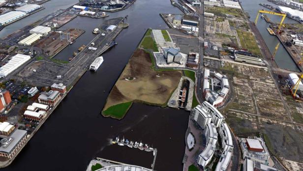 Luftaufnahme des Hafens von Belfast mit einem riesigen Porträt auf einer Grünfläche.