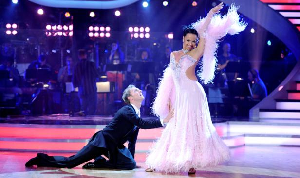 Ein Tanzpaar führt auf einer Bühne eine elegante Tanzpose vor.