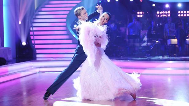 Ein Tanzpaar führt auf einer Bühne einen eleganten Tanz vor.