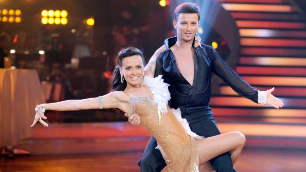 Ein Tanzpaar führt eine Hebefigur auf einer Bühne auf.