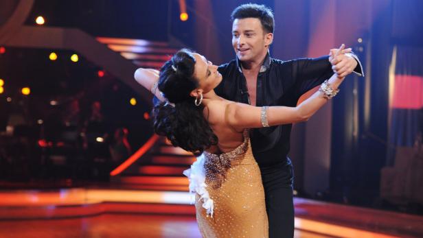 Ein Tanzpaar führt eine elegante Tanzbewegung auf einer Bühne aus.