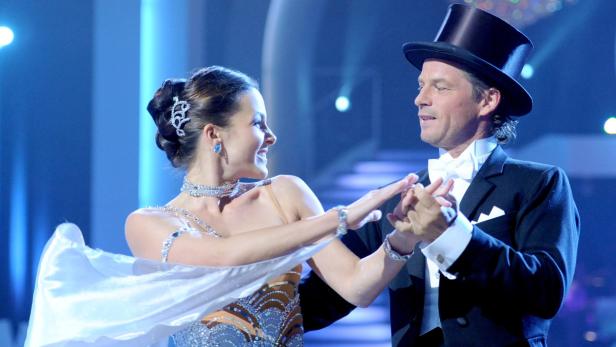 Ein Mann mit Zylinder und eine Frau im glitzernden Kleid tanzen zusammen.