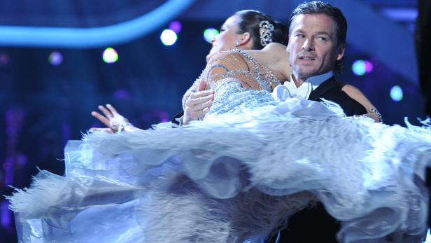 Ein Tanzpaar führt eine elegante Drehung auf einer Bühne auf..