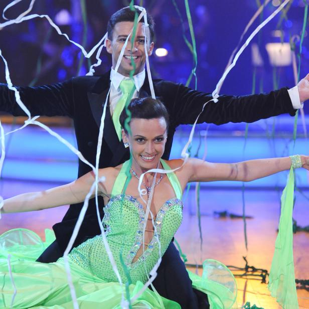 Ein Tanzpaar in grünen Kostümen tanzt unter Konfetti.