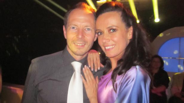 Ein Mann mit Krawatte und eine Frau posieren lächelnd für ein Foto.