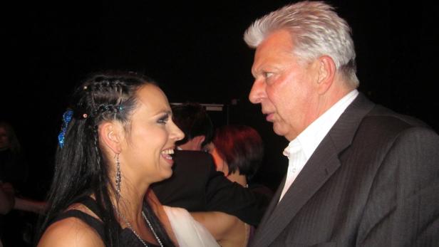 Eine lächelnde Frau mit Zöpfen und ein Mann im Anzug unterhalten sich.