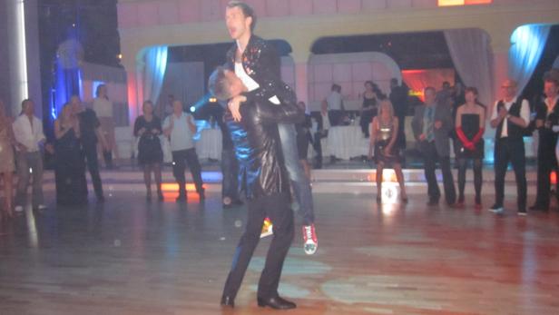 Ein Mann trägt einen anderen Mann auf seinen Schultern auf einer Tanzfläche.