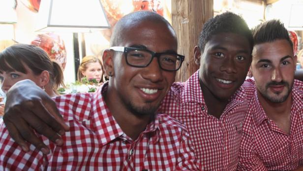 Drei Männer in rot-weiß karierten Hemden posieren lächelnd für ein Foto.