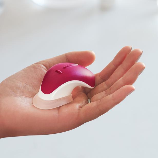 Eine Hand hält ein kleines, pinkfarbenes Massagegerät.